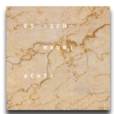 Die QLOCKTWO EARTH 90 in DESERT ist in der Front Ansicht. Ein stilvolles Kunstwerk wo jedes Exemplar ist ein Unikat, gefertigt auf echtem Stein.   Und das ikonische Buchstabenraster, das die Uhrzeit in Worten darstellt.